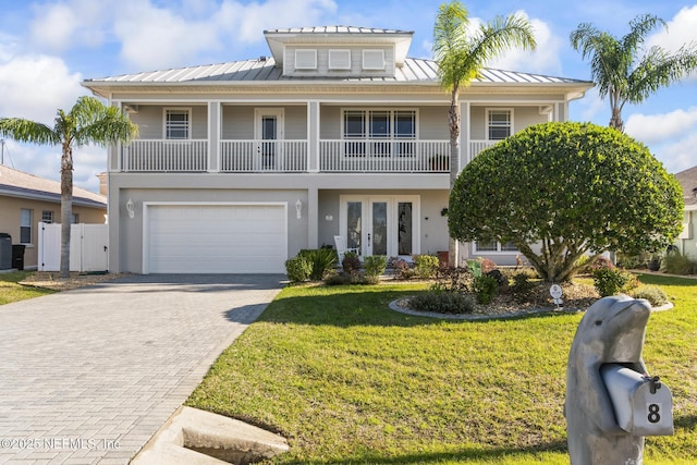 view of front facade featuring a standing seam roof, fence, decorative driveway, french doors, and a front yard