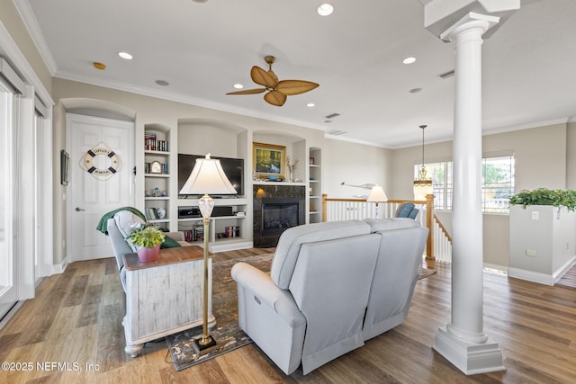 living area featuring ornate columns, crown molding, and wood finished floors