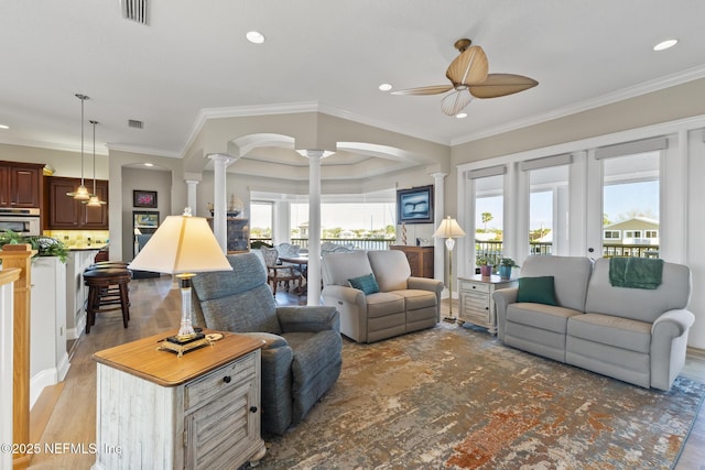 living room featuring decorative columns, visible vents, arched walkways, and a wealth of natural light