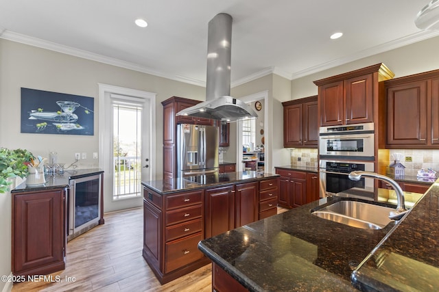 kitchen with reddish brown cabinets, wine cooler, stainless steel appliances, a sink, and island range hood