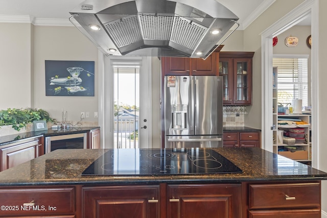 kitchen featuring stainless steel fridge with ice dispenser, wall chimney exhaust hood, a kitchen island, ornamental molding, and black electric stovetop