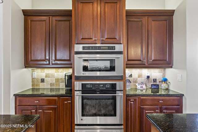 kitchen featuring stainless steel double oven, a warming drawer, backsplash, and dark stone countertops