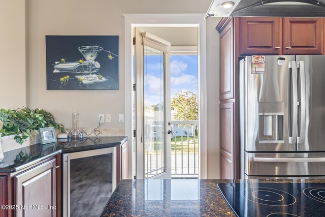 kitchen featuring dark stone counters, wine cooler, cooktop, and stainless steel fridge