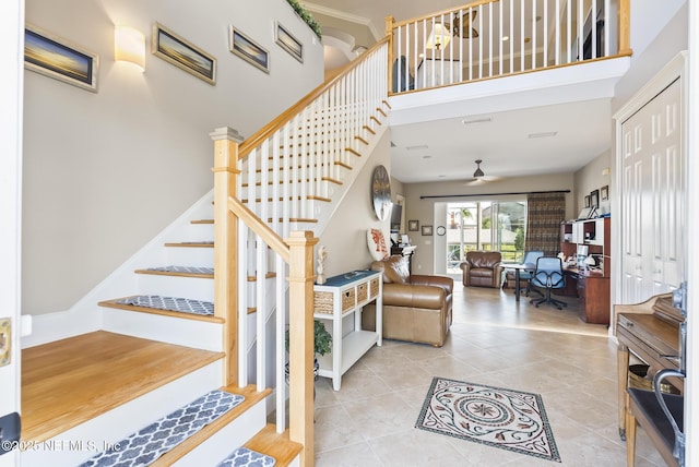 stairway with a towering ceiling, tile patterned flooring, and ceiling fan