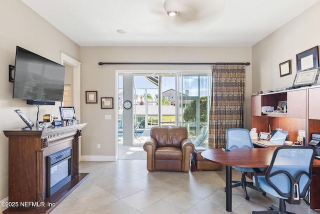 office featuring baseboards, light tile patterned flooring, and a glass covered fireplace