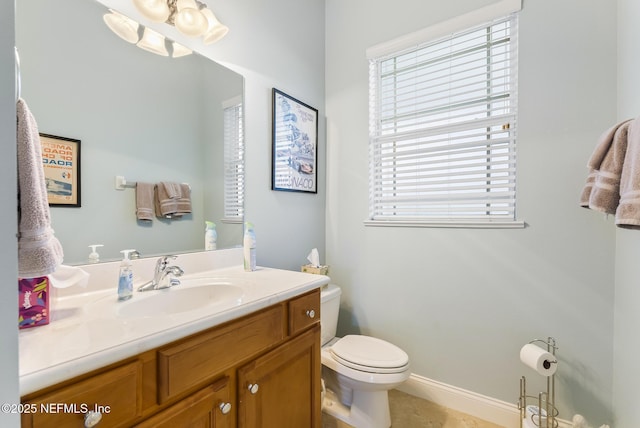 bathroom with toilet, baseboards, and vanity