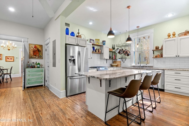 kitchen with stainless steel appliances, light stone countertops, light wood-style floors, and open shelves