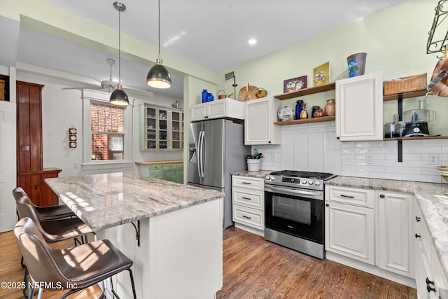 kitchen with a kitchen island, appliances with stainless steel finishes, open shelves, and dark wood finished floors