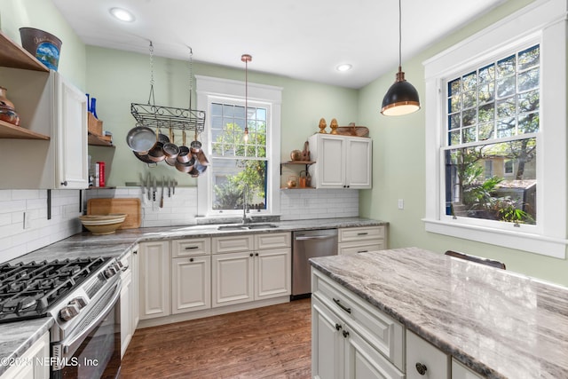 kitchen featuring wood finished floors, decorative light fixtures, stainless steel appliances, open shelves, and a sink