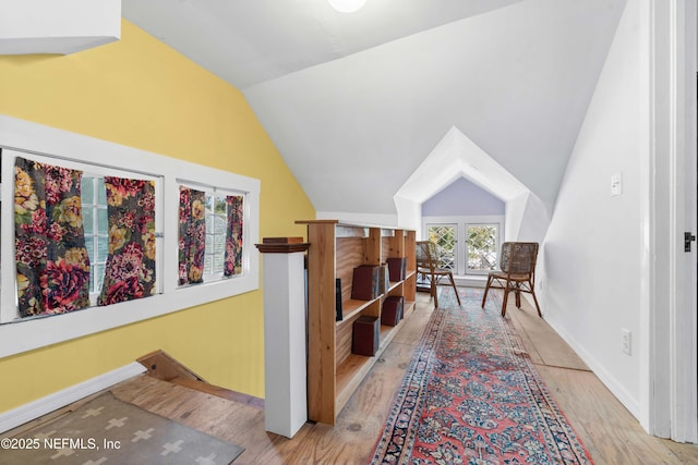 sitting room featuring vaulted ceiling, wood finished floors, an upstairs landing, and baseboards