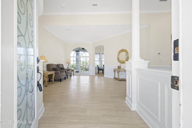 entryway with arched walkways, a wainscoted wall, decorative columns, a decorative wall, and ornamental molding