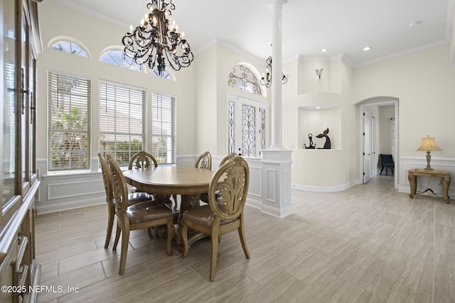 dining space featuring arched walkways, ornamental molding, decorative columns, and a decorative wall