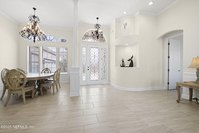 entrance foyer featuring ornate columns, ornamental molding, and an inviting chandelier