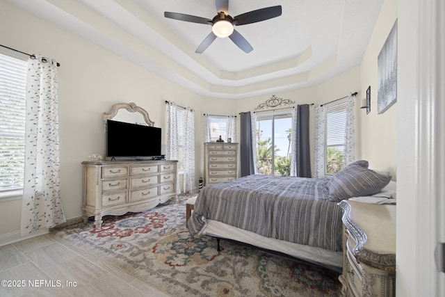 bedroom with ceiling fan, baseboards, and a raised ceiling