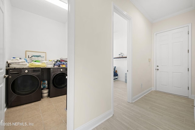 washroom with laundry area, light wood finished floors, baseboards, washer and clothes dryer, and crown molding