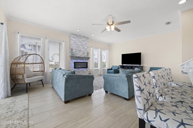 living area with ceiling fan, ornamental molding, a fireplace, and visible vents