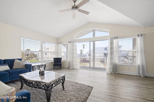 living room with a ceiling fan, vaulted ceiling, baseboards, and wood finished floors