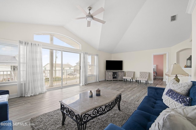 living room with lofted ceiling, wood finished floors, visible vents, baseboards, and a ceiling fan