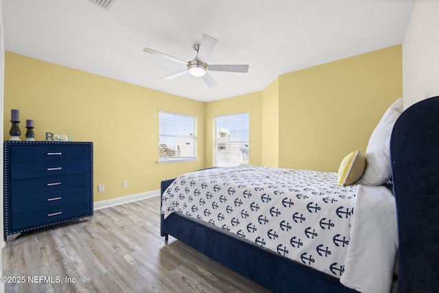 bedroom featuring ceiling fan, a textured ceiling, baseboards, and wood finished floors