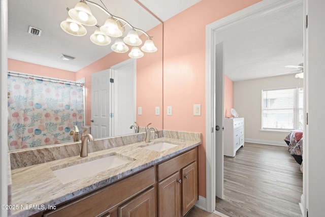 full bath featuring double vanity, visible vents, a sink, and wood finished floors