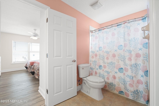 bathroom featuring a textured ceiling, curtained shower, tile patterned flooring, toilet, and visible vents