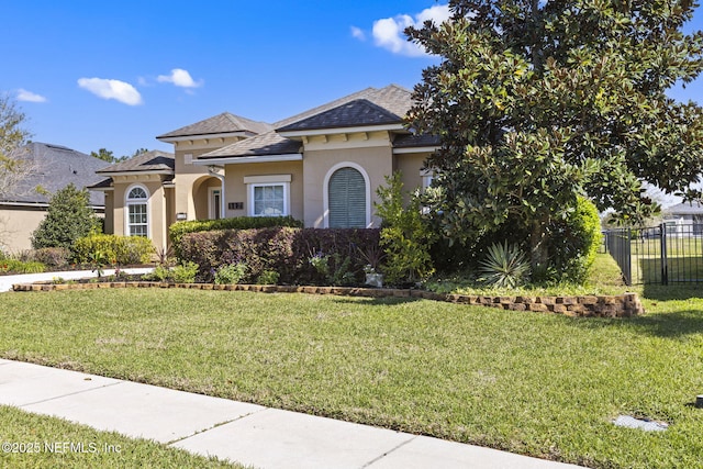 mediterranean / spanish-style home with stucco siding, a front lawn, and fence