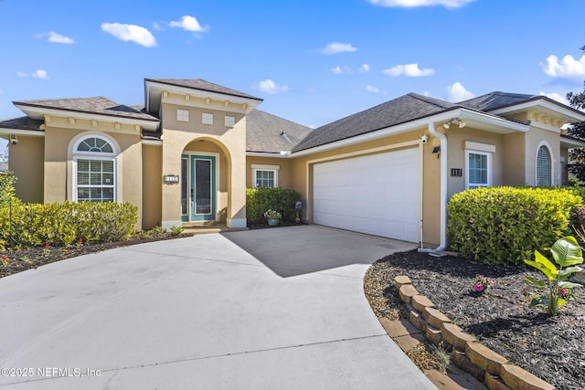 view of front of property with stucco siding, driveway, roof with shingles, and an attached garage