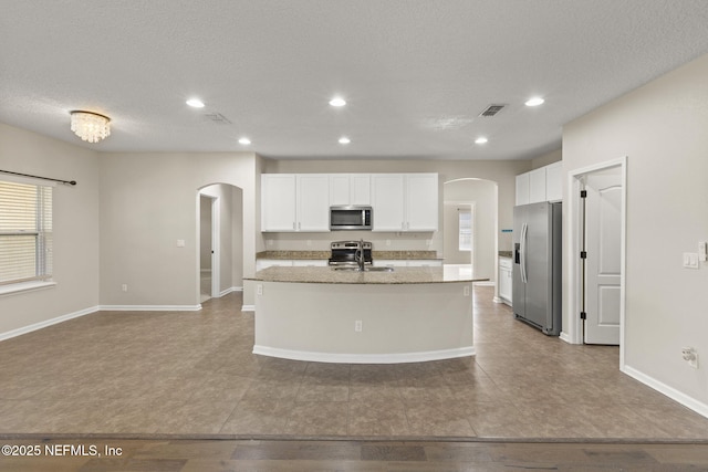 kitchen featuring arched walkways, visible vents, appliances with stainless steel finishes, and a sink