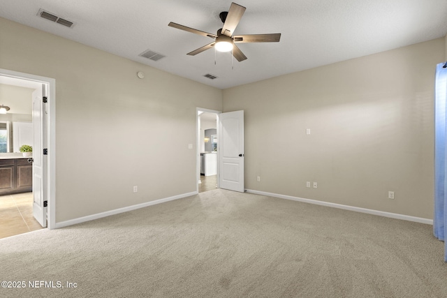 unfurnished bedroom with visible vents, baseboards, light colored carpet, and connected bathroom