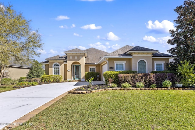 mediterranean / spanish-style home featuring a garage, stucco siding, concrete driveway, and a front lawn