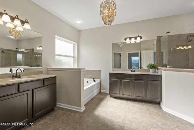 full bathroom featuring a garden tub, two vanities, a sink, an inviting chandelier, and tiled shower