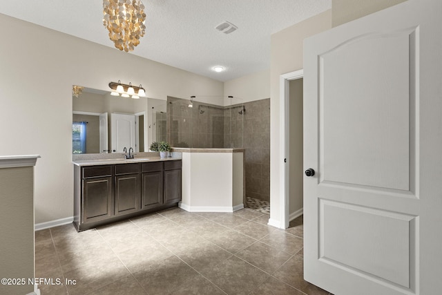 full bath with tile patterned floors, visible vents, a walk in shower, a textured ceiling, and vanity