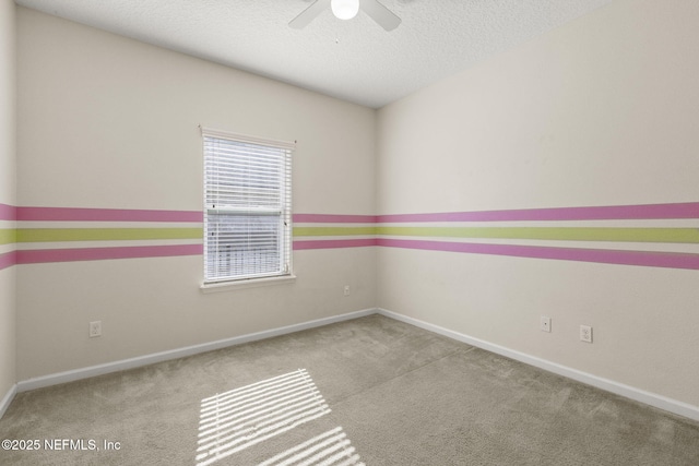 carpeted spare room featuring baseboards, a textured ceiling, and a ceiling fan