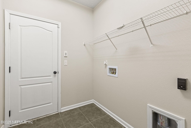 laundry room with dark tile patterned floors, laundry area, baseboards, and washer hookup