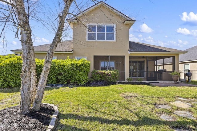 rear view of property featuring a yard, fence, stucco siding, and a sunroom