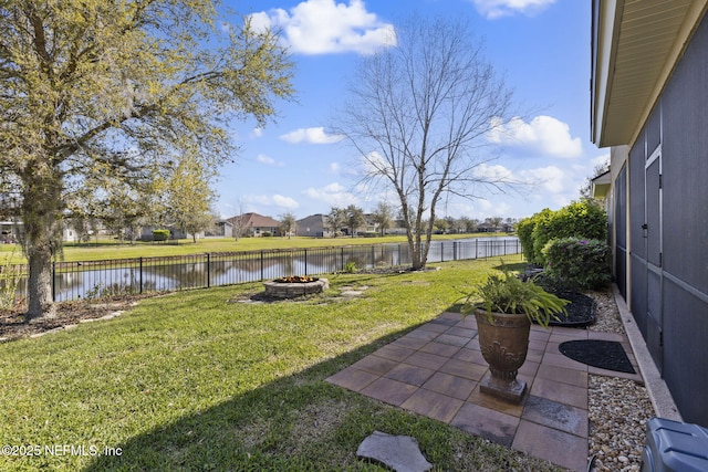 view of yard featuring a patio area, a water view, a fenced backyard, and a fire pit