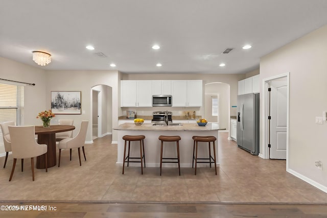 kitchen featuring visible vents, a breakfast bar, arched walkways, a sink, and appliances with stainless steel finishes