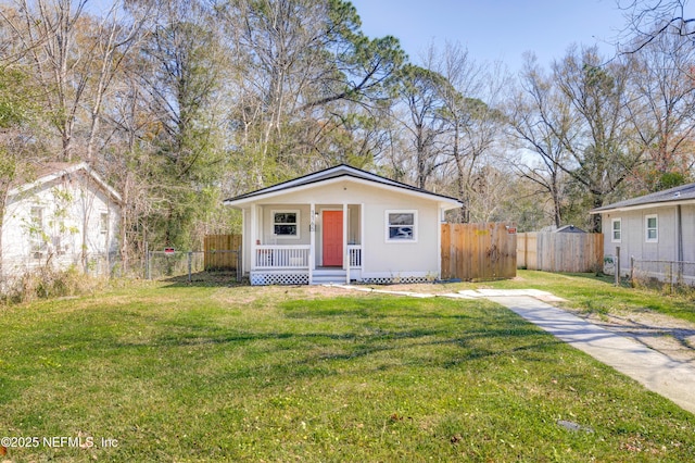 bungalow with covered porch, fence, and a front yard