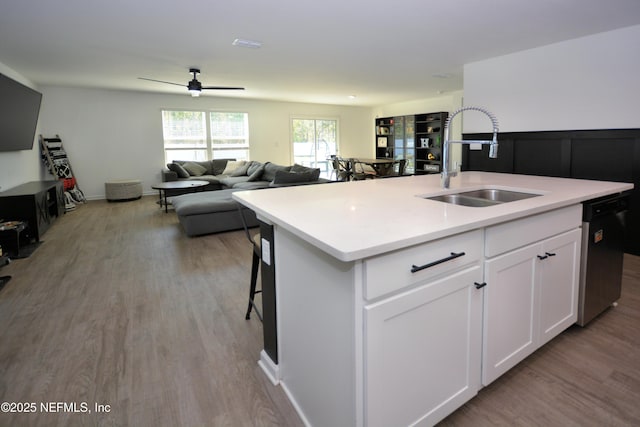 kitchen with a kitchen island with sink, dishwasher, a sink, and wood finished floors