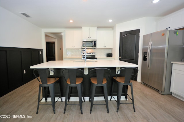 kitchen featuring a sink, visible vents, light countertops, appliances with stainless steel finishes, and backsplash