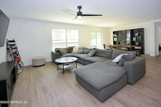 living room featuring light wood finished floors, a ceiling fan, and baseboards