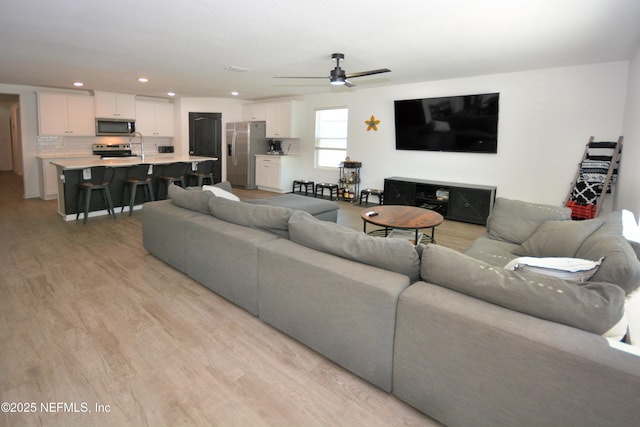 living room with light wood finished floors, a ceiling fan, and recessed lighting