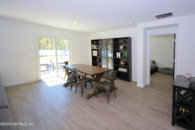 dining room with light wood-style flooring, visible vents, and baseboards