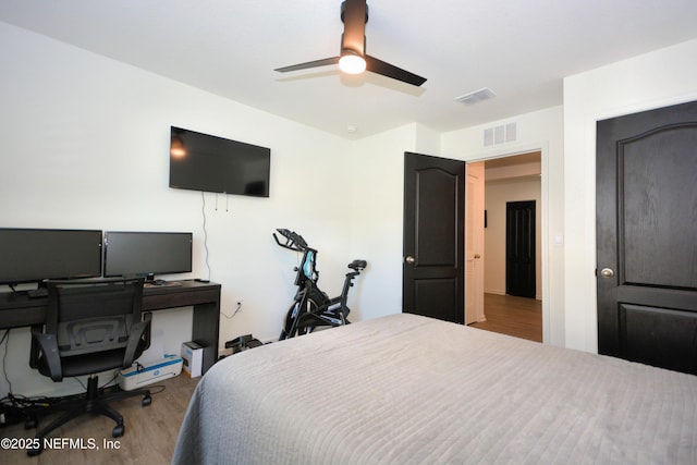 bedroom with a ceiling fan, visible vents, and wood finished floors