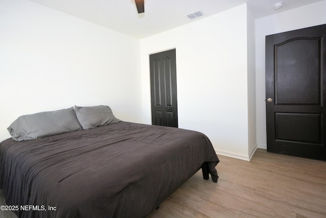 bedroom featuring light wood-style flooring, a ceiling fan, visible vents, and baseboards