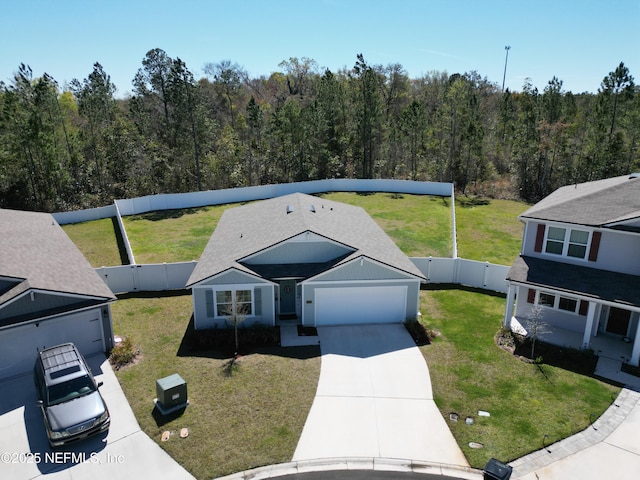 view of front of house featuring an attached garage, fence private yard, driveway, a front yard, and a view of trees