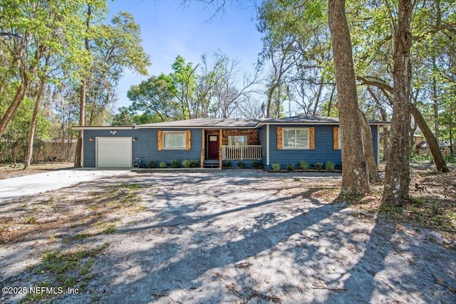 ranch-style home featuring covered porch, driveway, and an attached garage