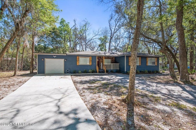 ranch-style house with a porch, concrete driveway, and an attached garage