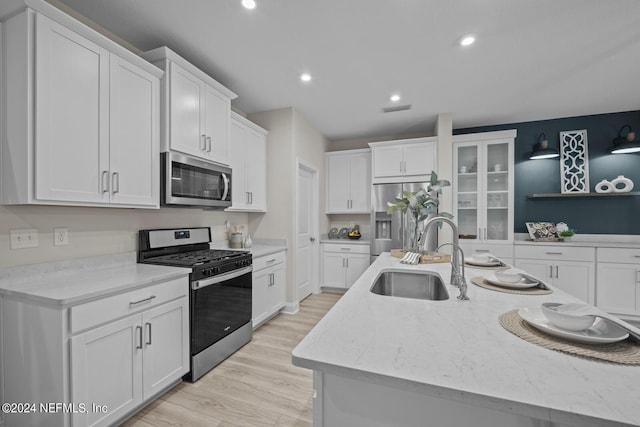 kitchen with recessed lighting, stainless steel appliances, a sink, white cabinetry, and light wood-style floors