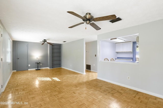 unfurnished living room featuring visible vents, built in shelves, baseboards, and ceiling fan